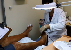 Profissional de jaleco branco e luvas aplica tratamento em pés de paciente