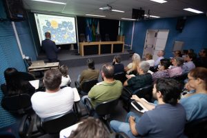 Foto de trabalhadores da Uerj no auditório da Reitoria. Léo Farias aparece à frente dando aula.